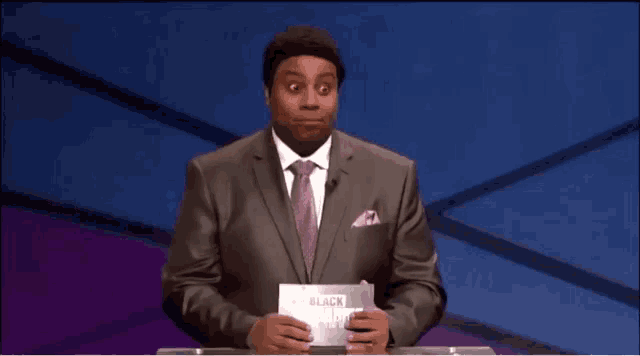 a man in a suit and tie is holding a sign that says " black history month "