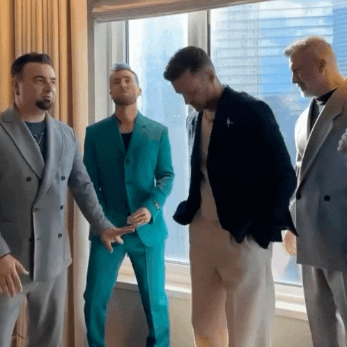 a group of men are standing in front of a window