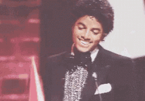 a man in a suit and tie is smiling and holding a microphone