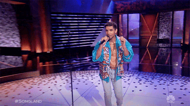 a man singing into a microphone on a stage with #songland on the bottom of the screen