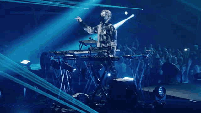 a man in a mask is playing a keyboard on a stage in front of a crowd