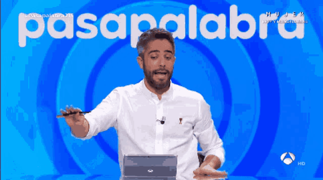 a man in a white shirt stands in front of a screen that says " pasapalabra "