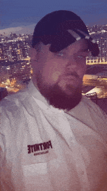 a man with a beard wears a white shirt with the word etintro on the pocket