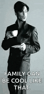 a man in a suit is holding a cup of coffee in his hand .