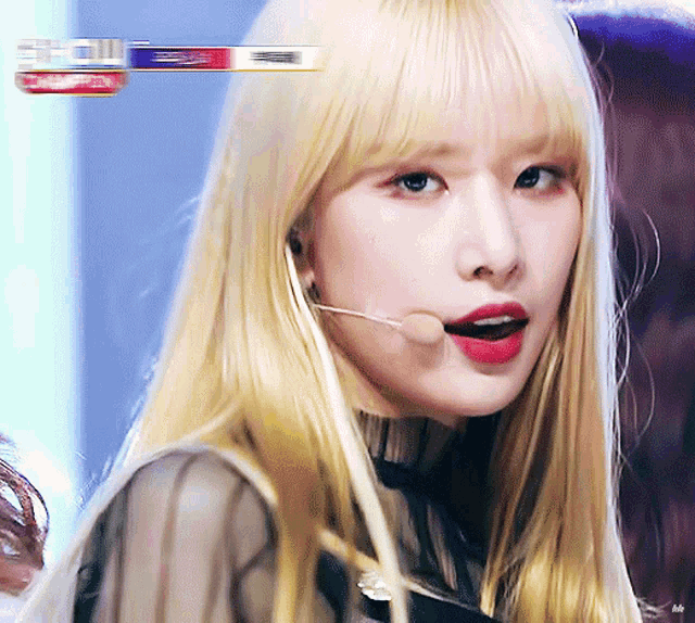 a woman with blonde hair and red lips is wearing a microphone in her mouth
