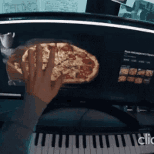 a person is holding a pizza in front of a keyboard that says clic