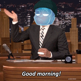 a man in a suit and tie is sitting at a desk saying good morning