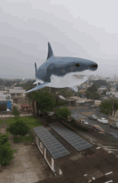 a shark is flying over a city with a cloudy sky