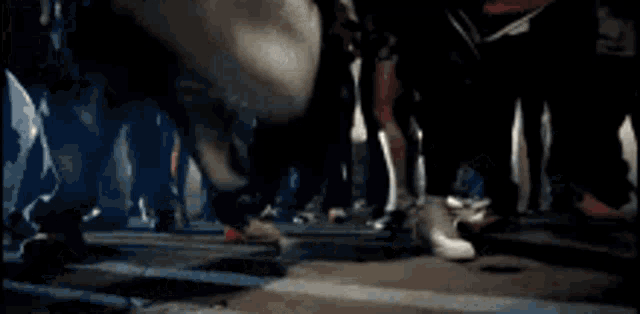 a person 's foot is visible in a blurry photo of a crowd of people dancing in a dark room .