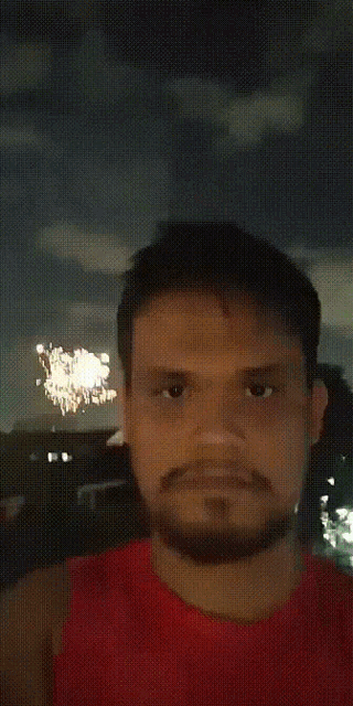 a man with a beard wearing a red shirt looks at the camera
