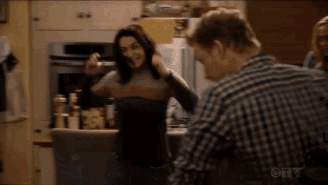 a man and a woman are dancing in a kitchen on a tv show .