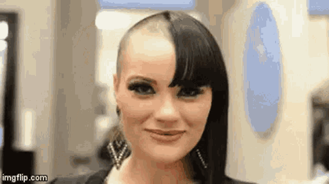 a woman with a shaved head and a half shaved head is smiling in a salon .