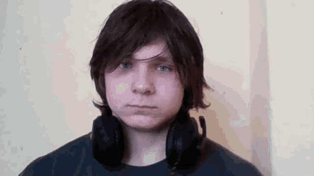 a young man wearing headphones and a black shirt is making a funny face .