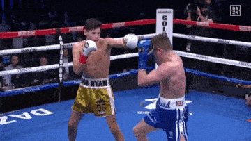 two boxers are fighting in a boxing ring and one of them is wearing shorts that say og
