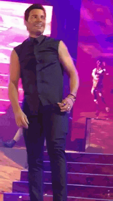 a man in a black vest is standing on stage