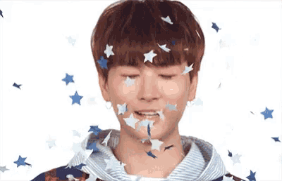 a young man is surrounded by stars falling on his face .