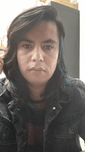 a man with long dark hair and blue streaks in his hair