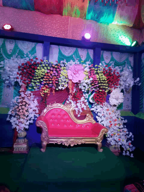 a pink and gold couch is surrounded by flowers and decorations