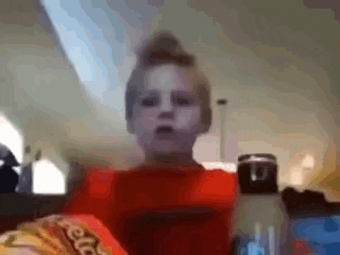 a child in a red shirt is eating cheetos