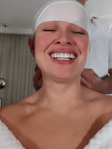 a woman with a white headband on her head smiles