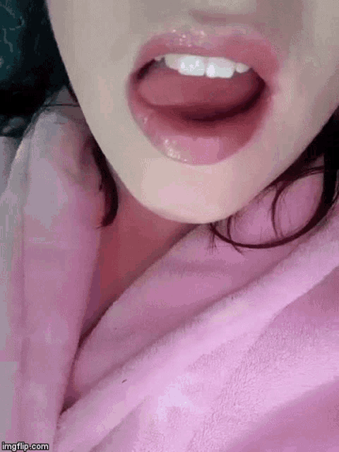 a close up of a woman 's mouth with her tongue sticking out while wearing a pink robe .
