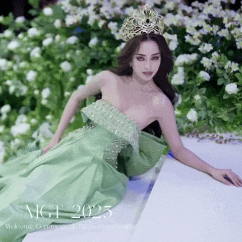 a woman in a green dress with a crown on her head is laying on the ground