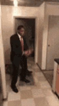 a man in a suit and tie is standing in a hallway in a room .