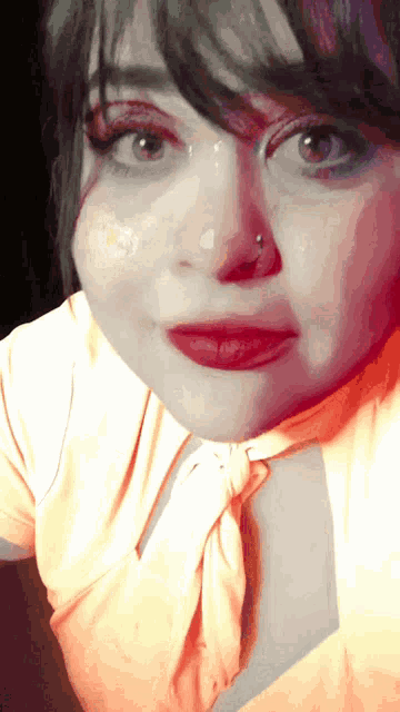 a close up of a woman 's face with a nose piercing