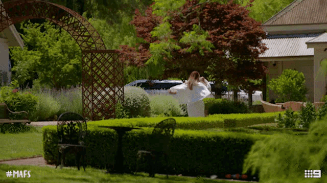 a woman in a white robe is standing in a garden with the hashtag # mafs