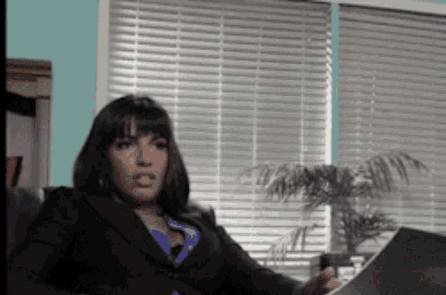 a woman in a business suit sits in front of a window