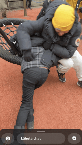 a phone screen shows a photo of a man carrying another man on his back and the words " lähetä chat " on the bottom