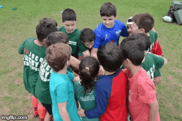 a group of children are huddled together and one of their shirts says " rugby "