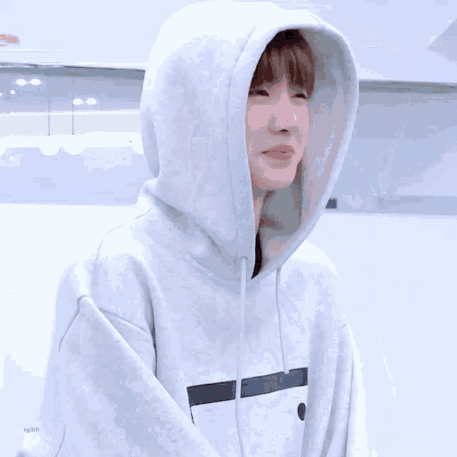 a young man wearing a white hoodie is smiling while holding a piece of paper .