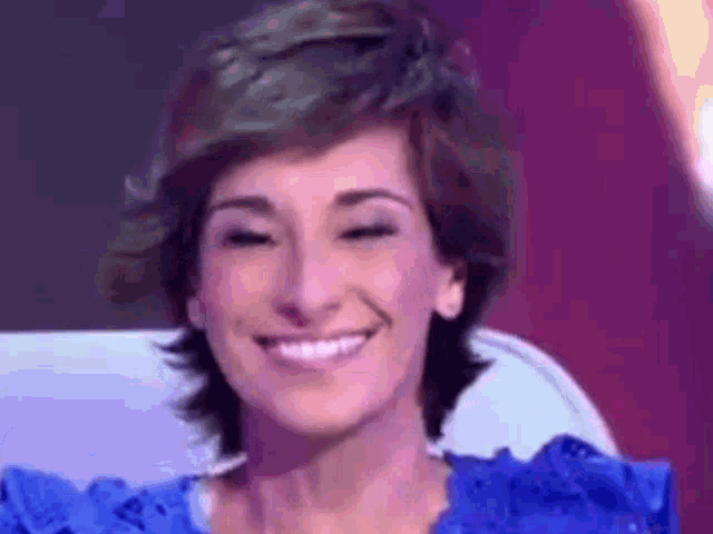 a woman in a blue dress is smiling while sitting on a chair .