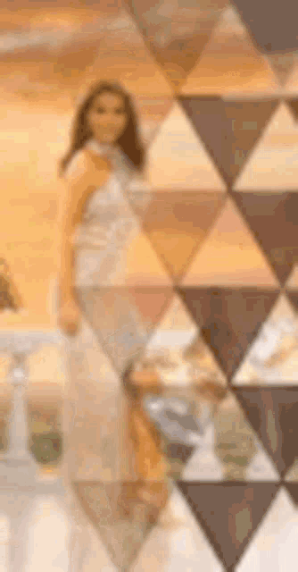 a woman in a long dress is standing in front of a geometric pattern .