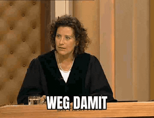 a woman is sitting at a table with a glass of water and a sign that says weg damit