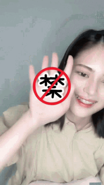 a woman holds up her hand in front of a red circle with chinese characters on it