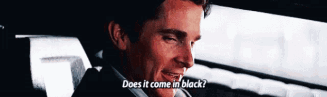 a man sitting in a car with the words " does it come in black " above him