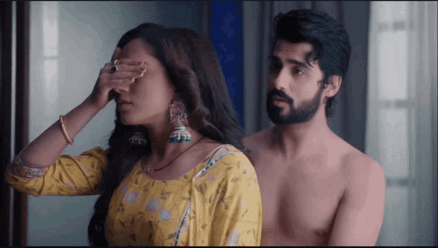 a shirtless man is standing next to a woman who is covering her eyes