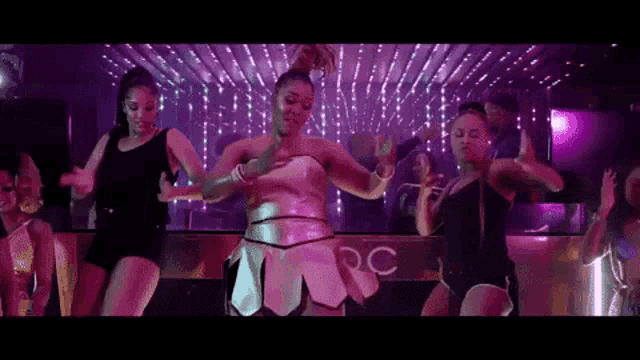a group of women are dancing in a club with the word rc in the background
