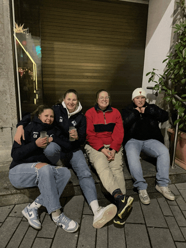 a group of people sitting on a sidewalk with one wearing a shirt that says ' ck ' on it