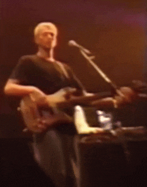 a man is playing a guitar and singing into a microphone