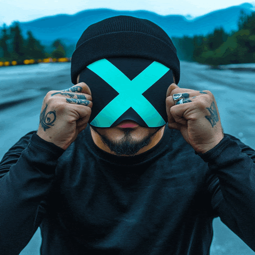 a man wearing a beanie and a mask with a blue x on it