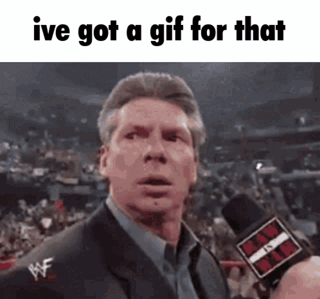 a man in a suit is talking into a microphone with the words `` ive got a gif for that '' below him .