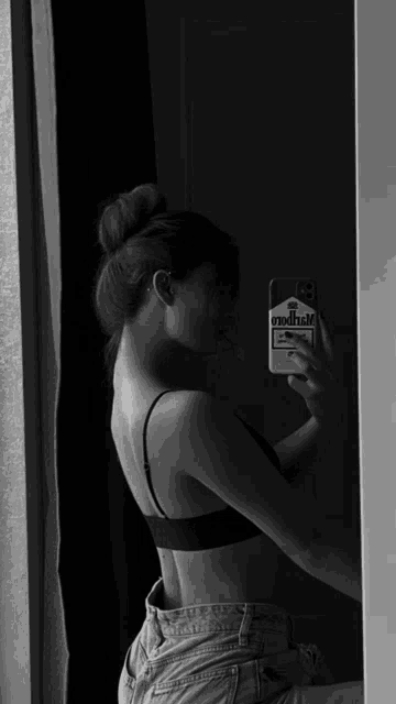 a woman is taking a selfie in front of a mirror with a marlboro sticker on her phone