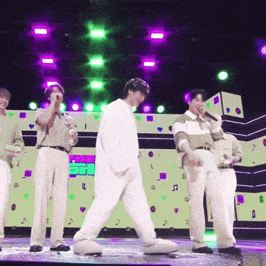 a group of men standing on a stage with purple lights behind them and a sign that says ' i love you '