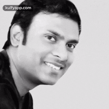 a black and white photo of a smiling man with the number 100 in red behind him