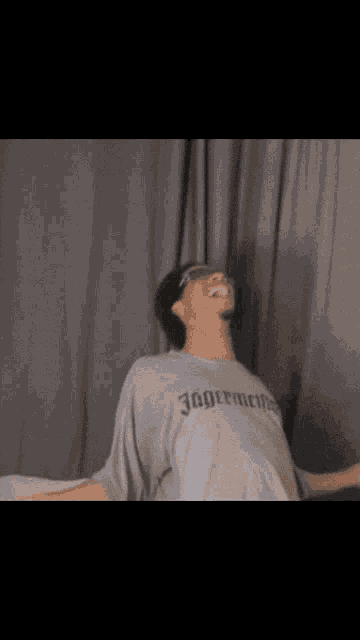 a man wearing a jagermeifer t-shirt is laughing with his eyes closed