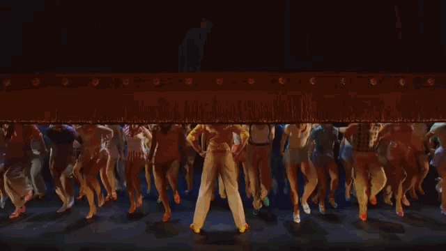 a group of people are dancing on a stage in a theatre .