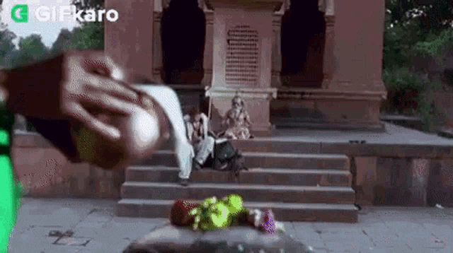 a woman is sitting on the steps of a temple while a man pours water on her .